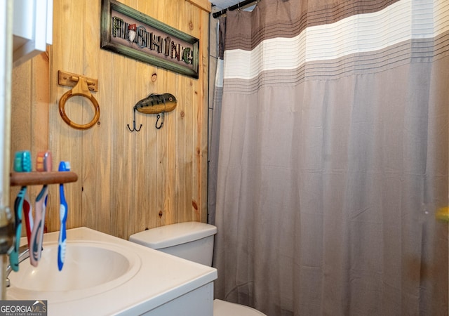 bathroom featuring toilet, wooden walls, vanity, and a shower with curtain