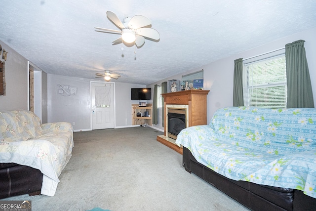carpeted living area with a fireplace, a textured ceiling, ceiling fan, and baseboards