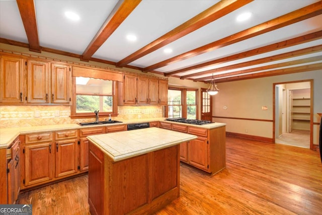 kitchen with a sink, a kitchen island, a peninsula, beam ceiling, and gas cooktop