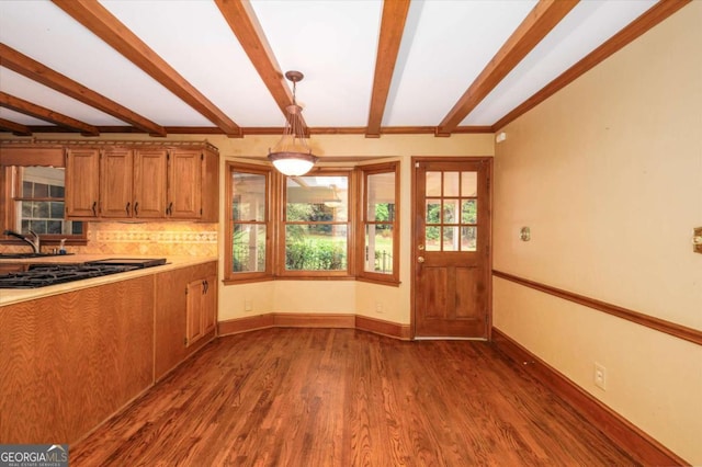 kitchen with black gas stovetop, beamed ceiling, wood finished floors, light countertops, and brown cabinetry