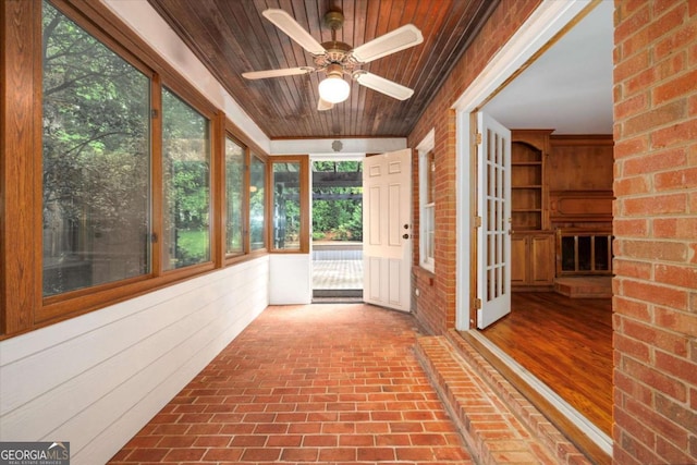 unfurnished sunroom with brick flooring, wood ceiling, and brick wall
