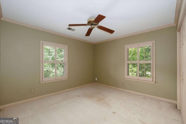 empty room with healthy amount of natural light, carpet floors, crown molding, and baseboards
