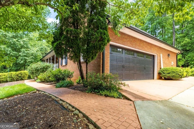 view of home's exterior featuring brick siding, an attached garage, and driveway