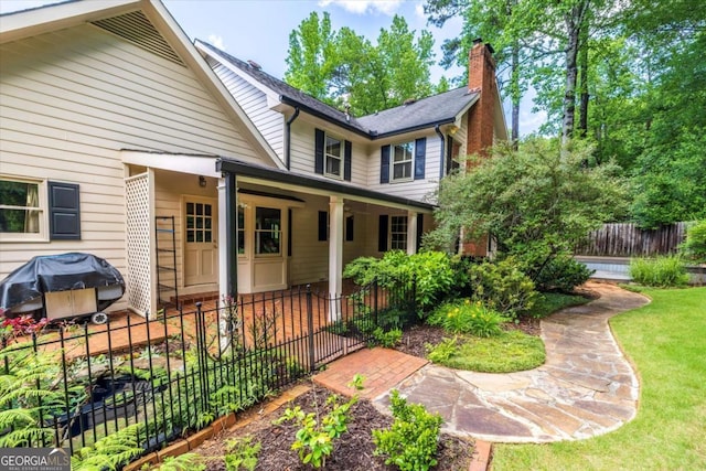 view of front of house featuring a chimney, fence, and a porch