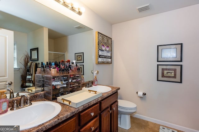 bathroom with a stall shower, double vanity, toilet, tile patterned floors, and baseboards