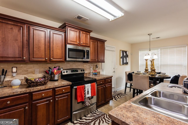 kitchen featuring stainless steel appliances, a sink, tasteful backsplash, pendant lighting, and baseboards