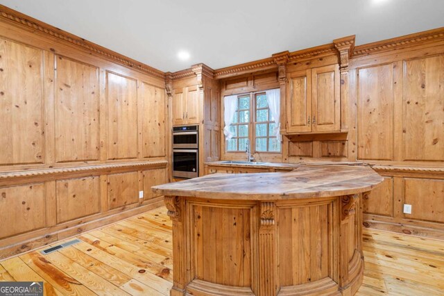 355 Clark Creek Pass, Acworth, GA 30102 - kitchen with open floor plan, light wood-style floors, double oven, ceiling fan, and wood walls