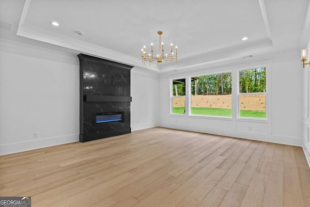 400 Auburn Rd, Auburn, GA 30011 - unfurnished living room featuring a raised ceiling, light wood-style floors, a chandelier, crown molding, and a premium fireplace
