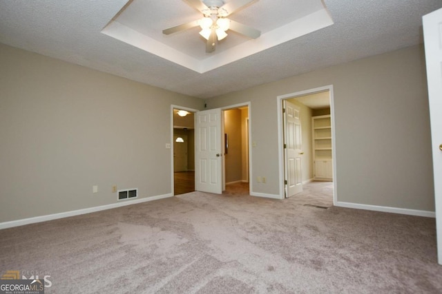 unfurnished bedroom with carpet floors, baseboards, a walk in closet, and a textured ceiling