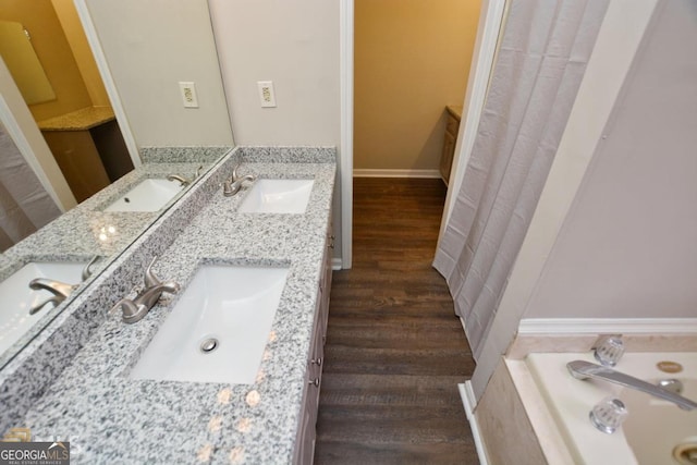 full bath featuring wood finished floors, double vanity, and a tub