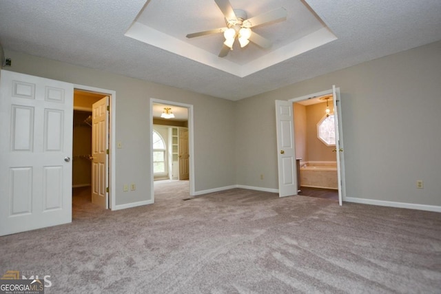 122 Wilson Cir, Carrollton, GA 30117 - unfurnished bedroom featuring a spacious closet, carpet, a tray ceiling, baseboards, and a textured ceiling