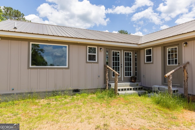 back of house with board and batten siding, metal roof, and french doors
