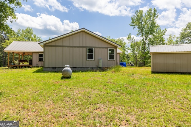 view of side of property featuring crawl space, a yard, a ceiling fan, and an outdoor structure