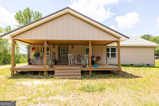 rear view of property featuring crawl space, metal roof, a yard, board and batten siding, and a deck