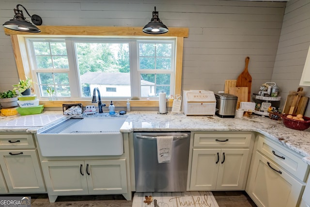 kitchen with stainless steel dishwasher, a sink, and light stone counters