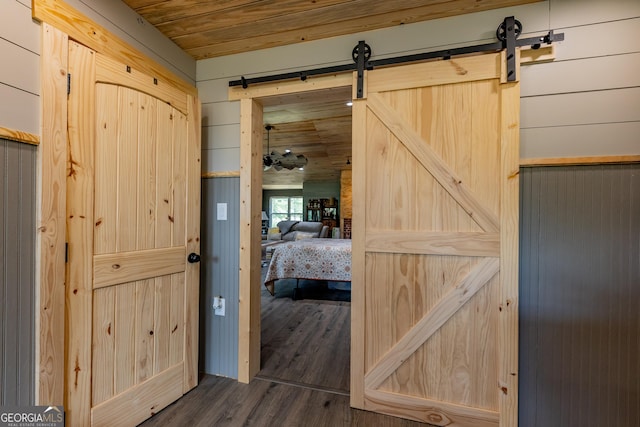 entryway featuring a barn door, dark wood finished floors, wooden ceiling, and wooden walls