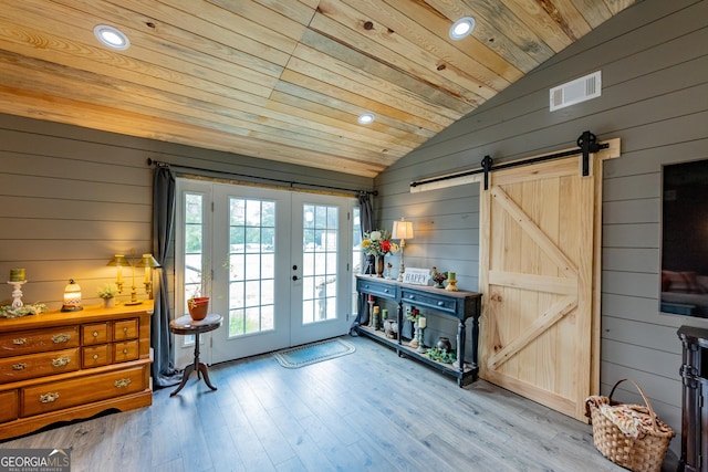 doorway featuring vaulted ceiling, french doors, wooden walls, wood ceiling, and a barn door