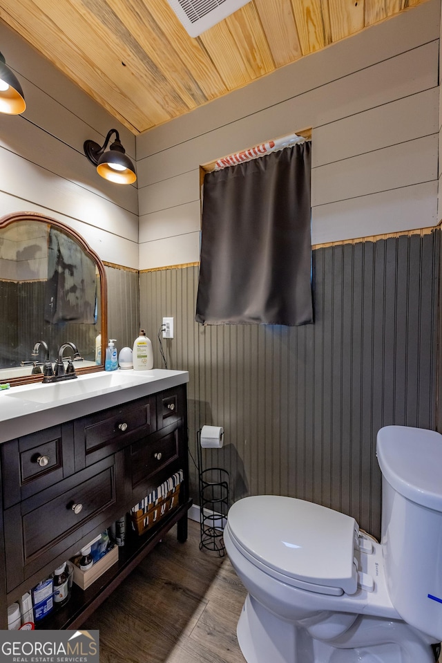 half bathroom with toilet, wood finished floors, and vanity
