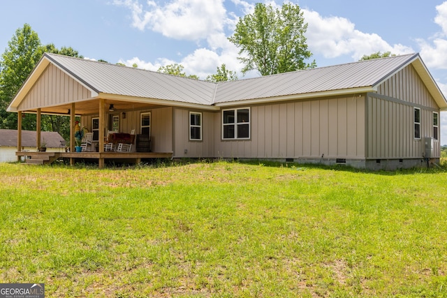 rear view of property featuring crawl space, a lawn, metal roof, and board and batten siding