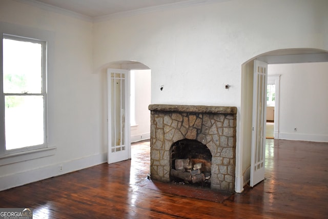 210 E Church St, Sandersville, GA 31082 - unfurnished living room with wood finished floors, baseboards, ornamental molding, a stone fireplace, and arched walkways