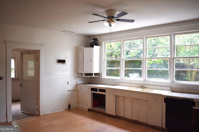 210 E Church St, Sandersville, GA 31082 - kitchen with a sink, a ceiling fan, light countertops, light wood-style flooring, and tile walls