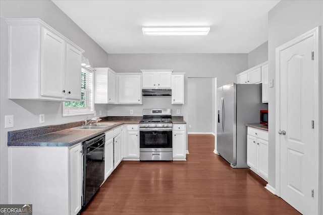 kitchen featuring stainless steel appliances, under cabinet range hood, a sink, dark wood-style flooring, and dark countertops