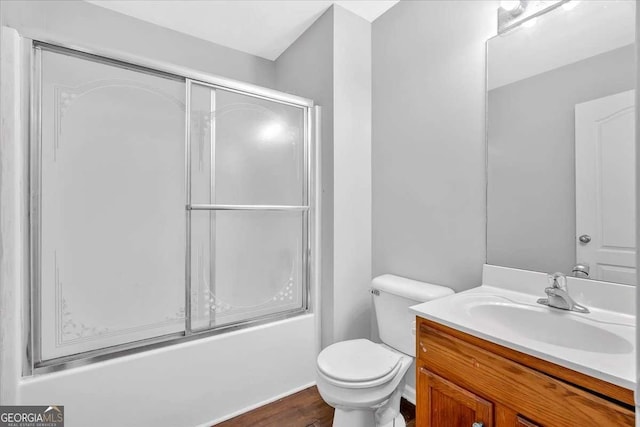 full bathroom with toilet, vanity, wood finished floors, and enclosed tub / shower combo