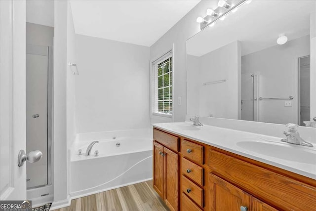 full bathroom with a shower stall, double vanity, wood finished floors, and a garden tub