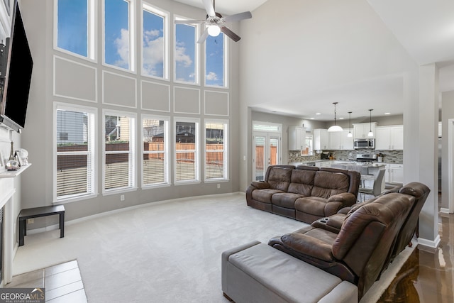 2430 Redbud Meadow Ln, Douglasville, GA 30135 - living room featuring a ceiling fan, a fireplace with flush hearth, baseboards, a towering ceiling, and light colored carpet