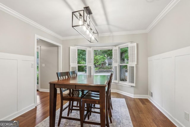 dining room featuring wood finished floors, ornamental molding, and a decorative wall