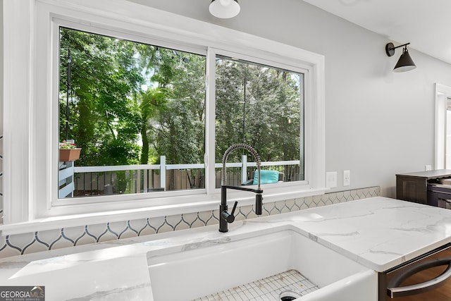 kitchen with a sink, light stone countertops, and dishwasher