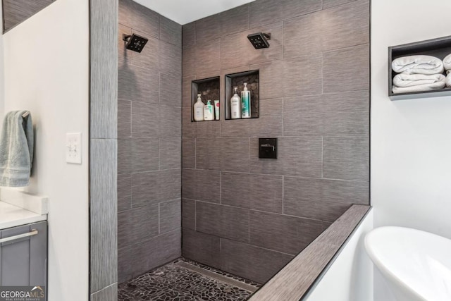 bathroom featuring tiled shower and vanity