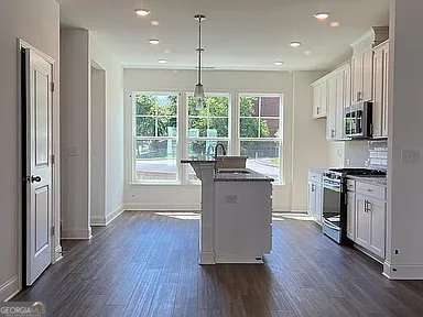 1616 Avery Way, Tucker, GA 30084 - kitchen with appliances with stainless steel finishes, a sink, dark wood finished floors, baseboards, and white cabinets
