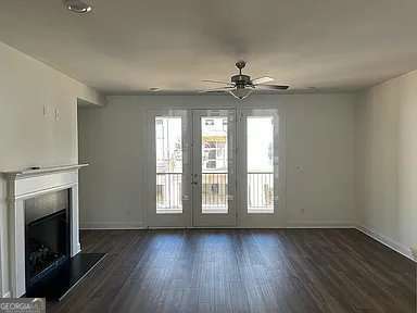 1616 Avery Way, Tucker, GA 30084 - unfurnished living room featuring ceiling fan, a fireplace, dark wood-type flooring, french doors, and baseboards