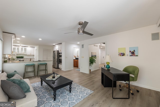 living room featuring light wood-style flooring, baseboards, ceiling fan, and recessed lighting