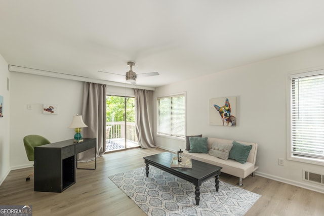 living area with healthy amount of natural light, light wood-style floors, a ceiling fan, and baseboards