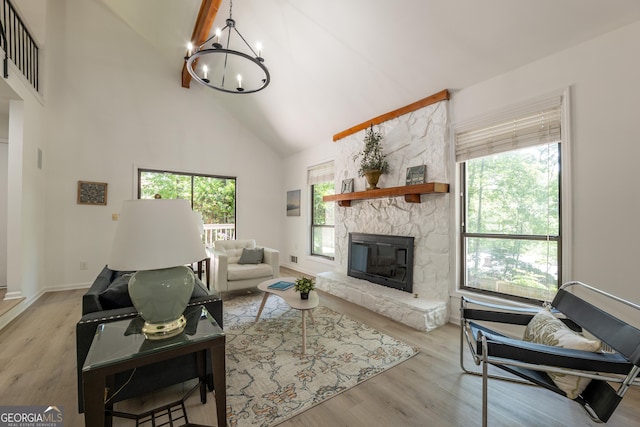 living area with a chandelier, high vaulted ceiling, healthy amount of natural light, a fireplace, and wood finished floors
