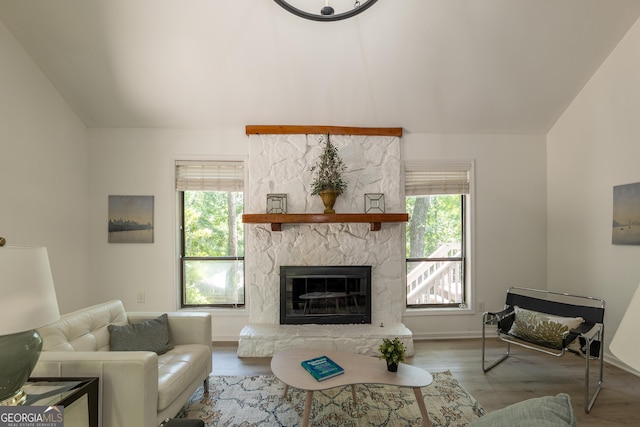 living area featuring healthy amount of natural light, a fireplace, wood finished floors, lofted ceiling, and baseboards