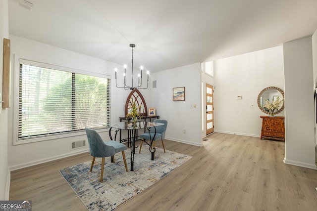 dining area with a chandelier, light wood finished floors, and baseboards