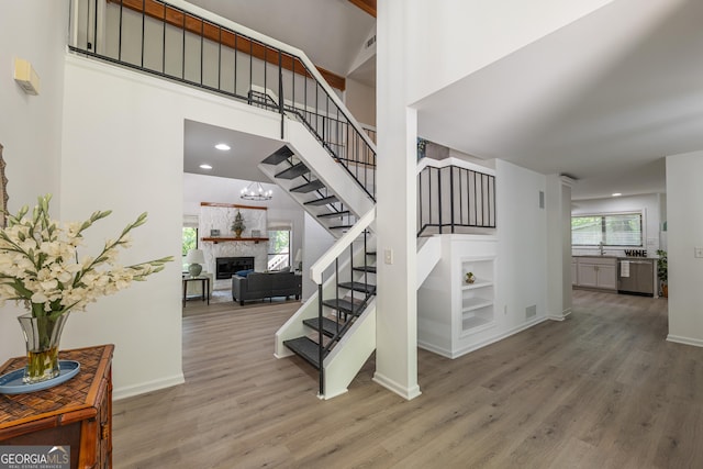 staircase with a high ceiling, wood finished floors, built in features, a fireplace, and baseboards