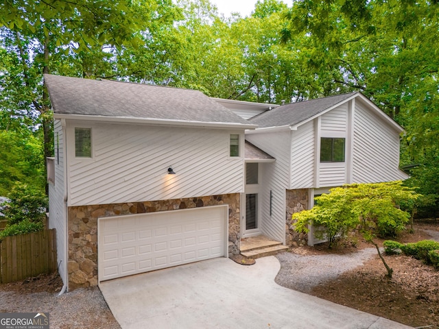 mid-century modern home with stone siding, roof with shingles, and driveway