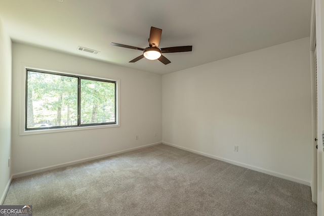 empty room featuring a ceiling fan, baseboards, and light colored carpet