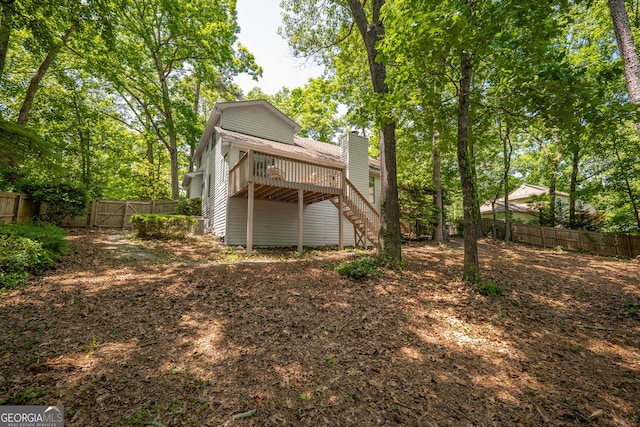 back of property featuring stairway, a fenced backyard, a deck, and a chimney