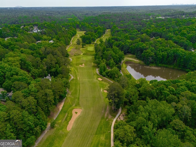 view of property location with a forest, a nearby body of water, and a golf course