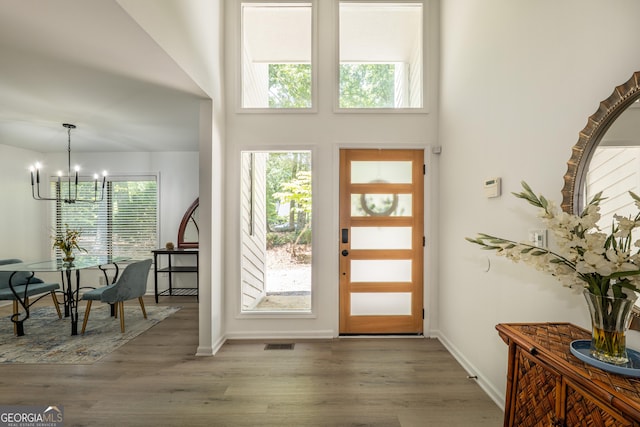 entryway with a chandelier, wood finished floors, and baseboards