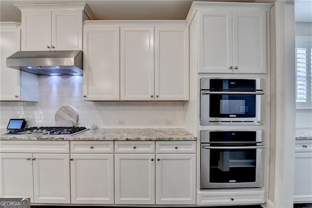 kitchen with appliances with stainless steel finishes, under cabinet range hood, and white cabinets
