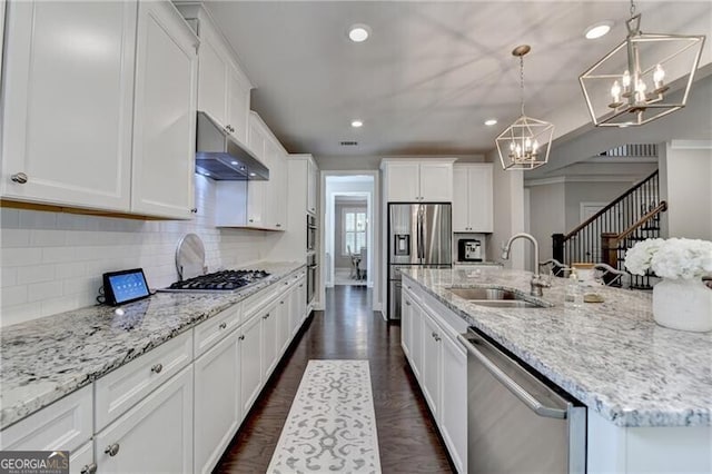 kitchen featuring appliances with stainless steel finishes, a sink, a chandelier, under cabinet range hood, and white cabinetry