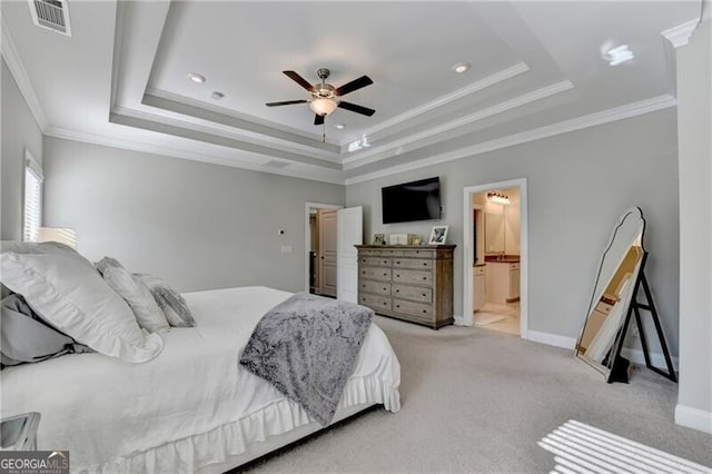 carpeted bedroom with a tray ceiling, ornamental molding, recessed lighting, baseboards, and ensuite bath