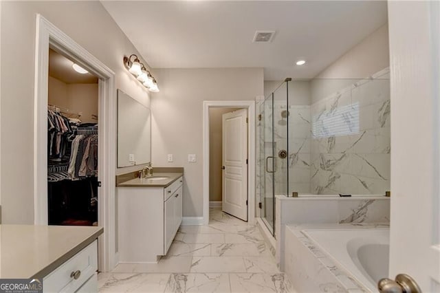 full bathroom with marble finish flooring, vanity, a marble finish shower, a garden tub, and a walk in closet