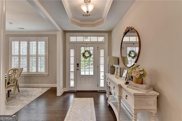 entrance foyer with crown molding, dark wood-style flooring, a tray ceiling, and baseboards